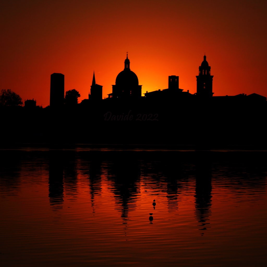 Mantova (Lombardia – Italia). Tramonto sul Lago Inferiore con il profilo del Palazzo Ducale, del campanile della basilica palatina di Santa Barbara e della cupola della basilica concattedrale di Sant’Andrea. Fotografia di Davide (ottobre 2022). © Davide Tansini